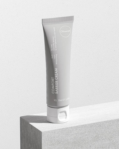 Olivarrier comfort barrier relief cream lifestyle image - the white bottle resting on a white block with wooden texture, against a white background